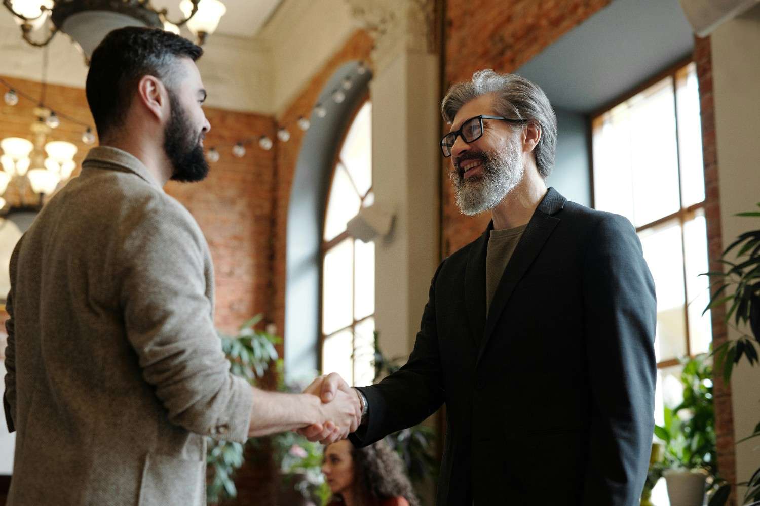 Professional insurance agent shaking hands with a happy customer near a modern sedan
